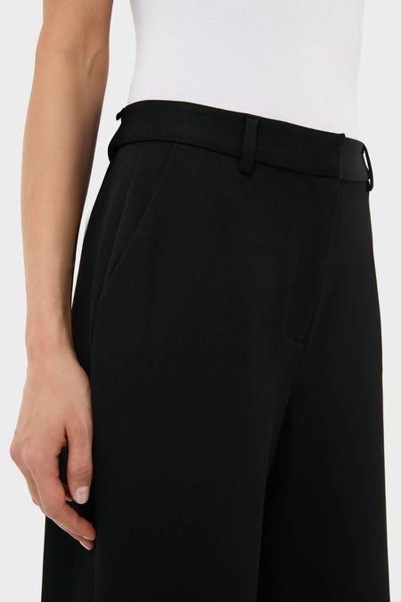 Model wearing Black Pillar Wide Leg Pant: classic, high-rise, wide-leg tailored trousers with effortless style, featuring a thin black belt and side pockets. Perfect for a fun, high-end look.