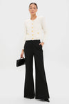 Model wearing classic Black Pillar Wide Leg Pant, high-rise and wide-leg, paired with a cream cardigan, embodying an effortless, fun, high-end style.