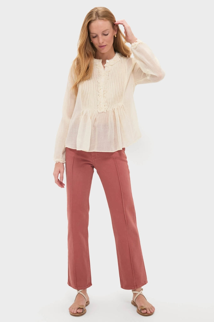 Young woman in classic Cowrie Adriel Blouse with pintucks and ruffles, paired with high-waisted flared pants, embodying an effortless, high-end style.