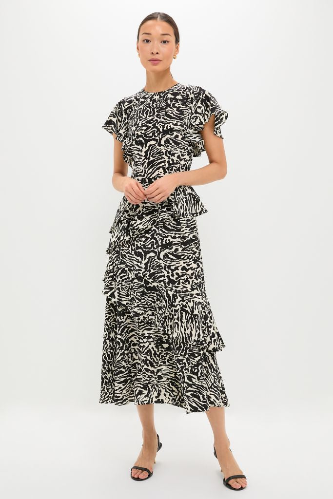 Woman models the Spotted Jasper Amaia Dress, a classic midi with an abstract pattern, flutter sleeves, and ruffled tiers, epitomizing effortless, high-end style and fun elegance.