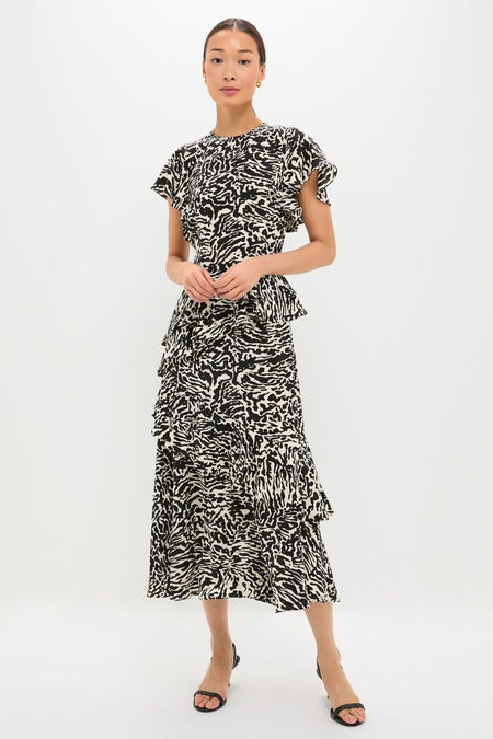 Woman models the Spotted Jasper Amaia Dress, a classic midi with an abstract pattern, flutter sleeves, and ruffled tiers, epitomizing effortless, high-end style and fun elegance.