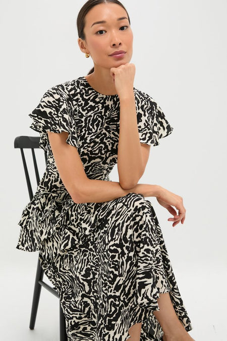 Spotted Jasper Amaia Dress on a seated woman, showcasing its classic fit-and-flare design, effortless flutter sleeves, and high-end tiered ruffles, perfect for fun, versatile occasions.