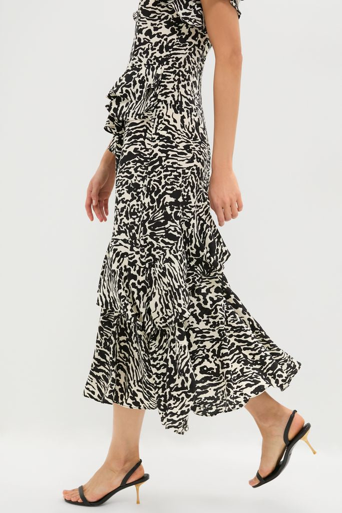 Person mid-stride in the Spotted Jasper Amaia Dress with zebra-like print, layered ruffles, and black sling-back kitten heels, showcasing classic, effortless, high-end fashion.
