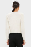 Ivory Una Knit Cardigan in a classic, effortless style, worn with tailored black trousers. Features a cropped silhouette, gold hoop earrings, and low ponytail.