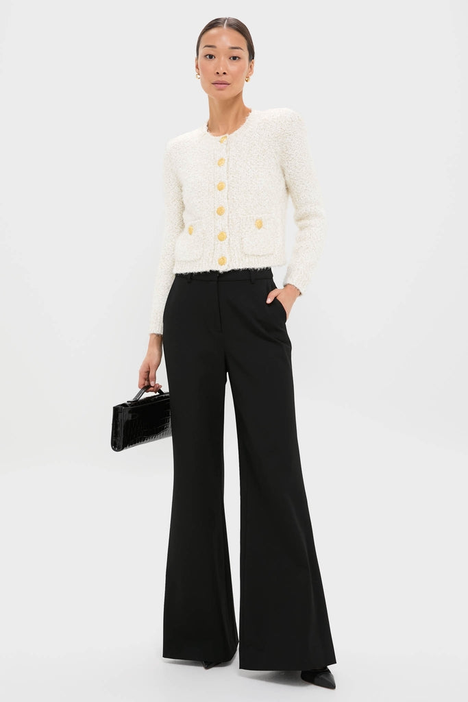 Ivory Una Knit Cardigan with gold crest buttons and patch pockets, styled effortlessly with black wide-leg trousers, embodies a classic, high-end, fun look.