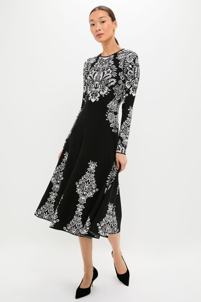 Noir Callista Dress: A classic, high-end black midi dress with an effortless, ornate white floral pattern, paired with black heels, embodying Tuckernuck's fun and confident style.