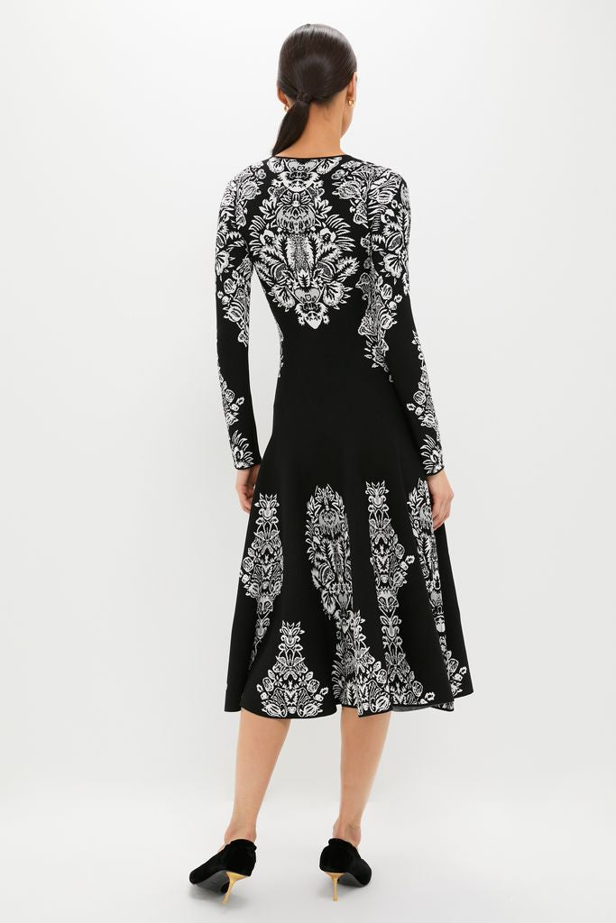 Woman in the Noir Callista Dress, a classic, fit-and-flare midi with an effortless black and white baroque floral print, embodying high-end style and fun sophistication.
