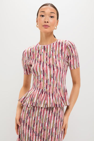 Model wearing the Rosewood Samira Pullover, a classic, multicolored knit top with a peplum flare, paired with a matching skirt and gold hoop earrings for an effortless, high-end look.