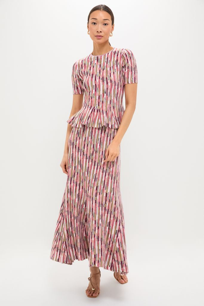 Woman in classic Rosewood Samira Pullover and matching skirt, featuring an effortless ribbed, knit design with vertical stripes, styled with strappy sandals and hoop earrings for a fun, high-end look.