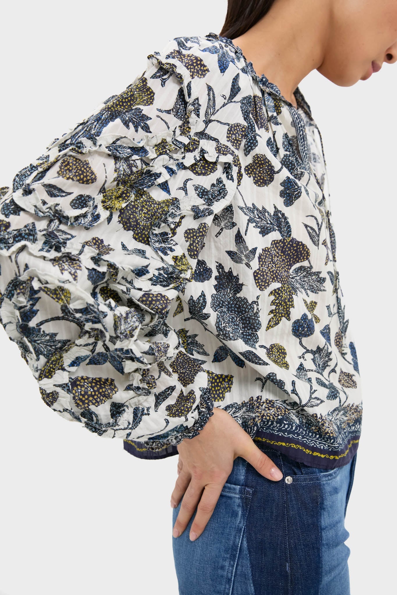 Classic Porcelain Azrou Blouse with blue and mustard floral prints, ruffled balloon sleeves, and neckties, paired effortlessly with medium-wash jeans for a high-end, fun look.