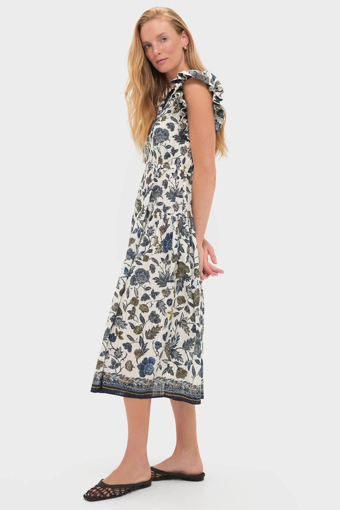 Young woman in the classic Porcelain Kairi Dress, showcasing an effortless, fun botanical print with ruffled cap sleeves and decorative hem, paired with high-end black woven sandals.