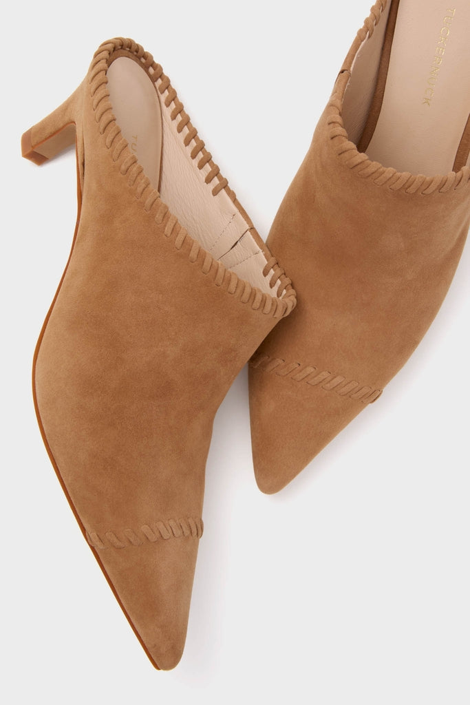 Camel Suede Whipstitch Kathryn Mules, classic and effortless, feature a pointed toe, block heel, and decorative whip-stitch trim, embodying Tuckernuck’s fun and high-end style.