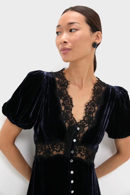 Young woman in a classic Navy Clarice Velvet Puff Sleeve Midi Dress, featuring an effortless lace-trimmed V-neckline, puffed sleeves, and a fun sheer lace midriff panel.