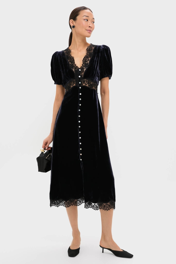 Woman models Navy Clarice Velvet Puff Sleeve Midi Dress; classic, effortless design with a deep V-neck, lace trims, puffed sleeves, and elegant button detailing.