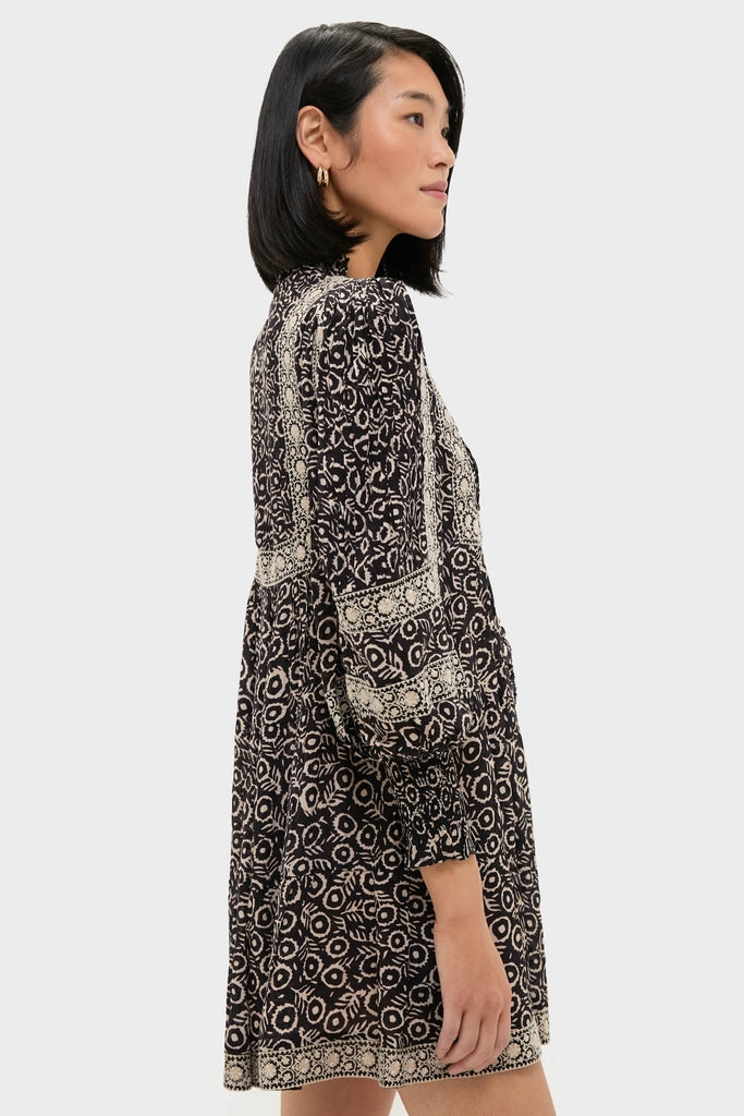 Young woman wearing the Multi Emmeline Print Long Sleeve Mini Tiered Dress, showcasing its classic, effortless style with fun patchwork patterns and high-end design.