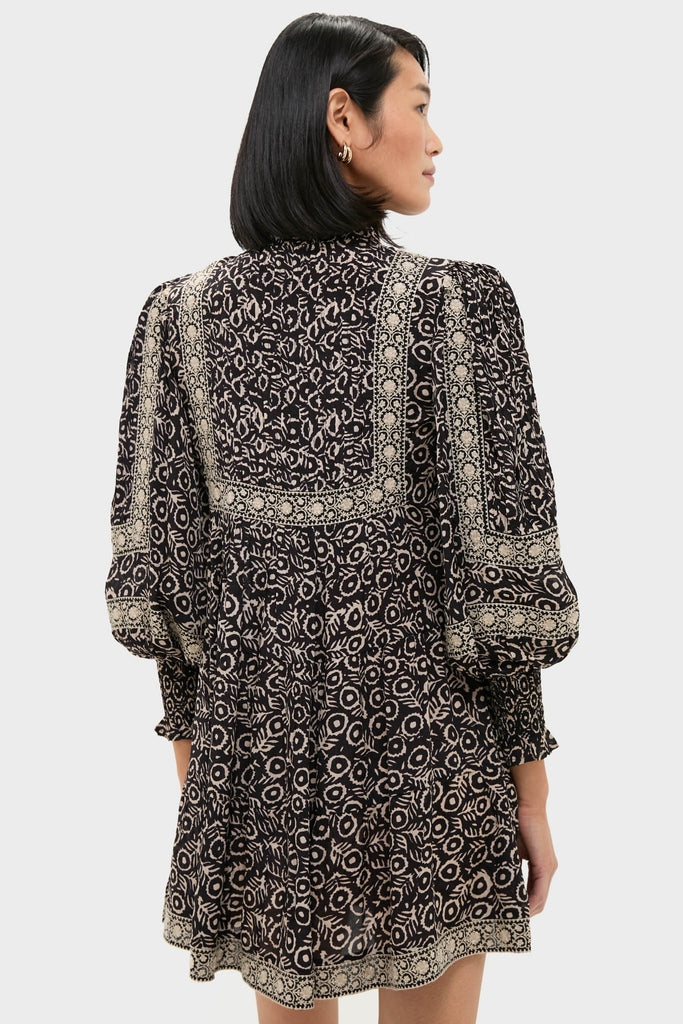 Woman models the Multi Emmeline Print Long Sleeve Mini Tiered Dress with classic floral print, showcasing its effortless elegance and fun puffed sleeves, embodying Tuckernuck’s high-end style.