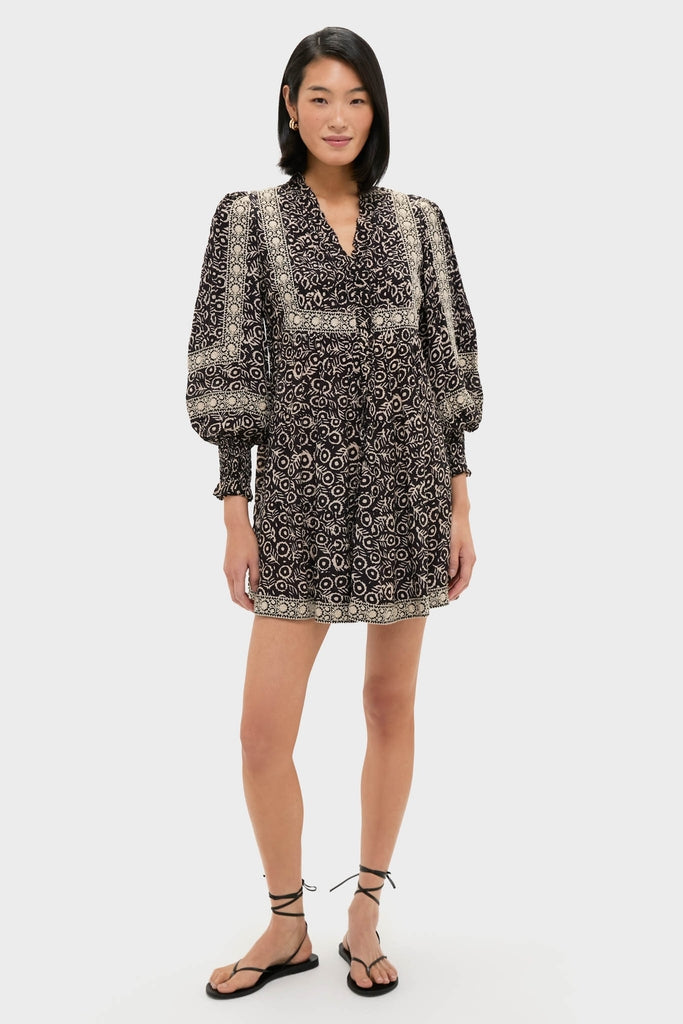 Model wearing the classic Multi Emmeline Print Long Sleeve Mini Tiered Dress with bohemian patterns, voluminous sleeves, and a tie neckline; styled with effortless, high-end flair.