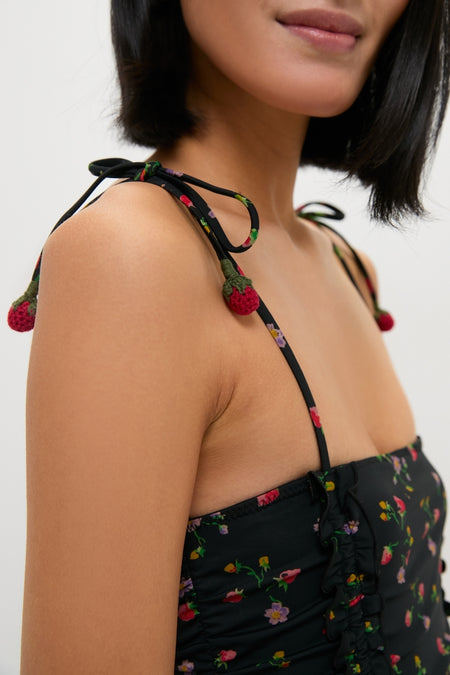 Woman wearing the Multi Katarina Print Tie Strap One Piece with adjustable tie-up straps and playful crochet strawberries, showcasing an effortless, fun, and high-end resort-ready style.