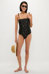 Woman in a classic, high-end Multi Katarina Print Tie Strap One Piece swimsuit with ruched sides, holding a straw hat, embodying an effortless, fun resort-ready style.