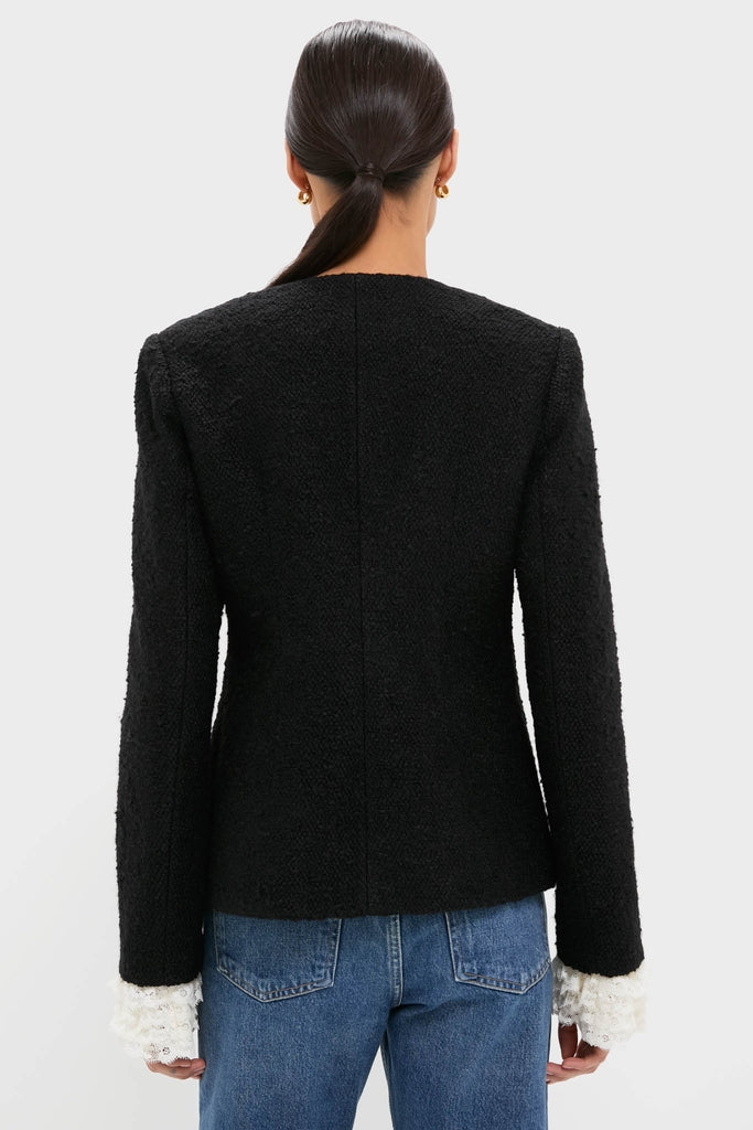 Woman in a classic, fitted Black Seraphine Solid Bow Jacket with white lace-trimmed sleeves, paired with medium-wash jeans, embodying an effortless, high-end style.