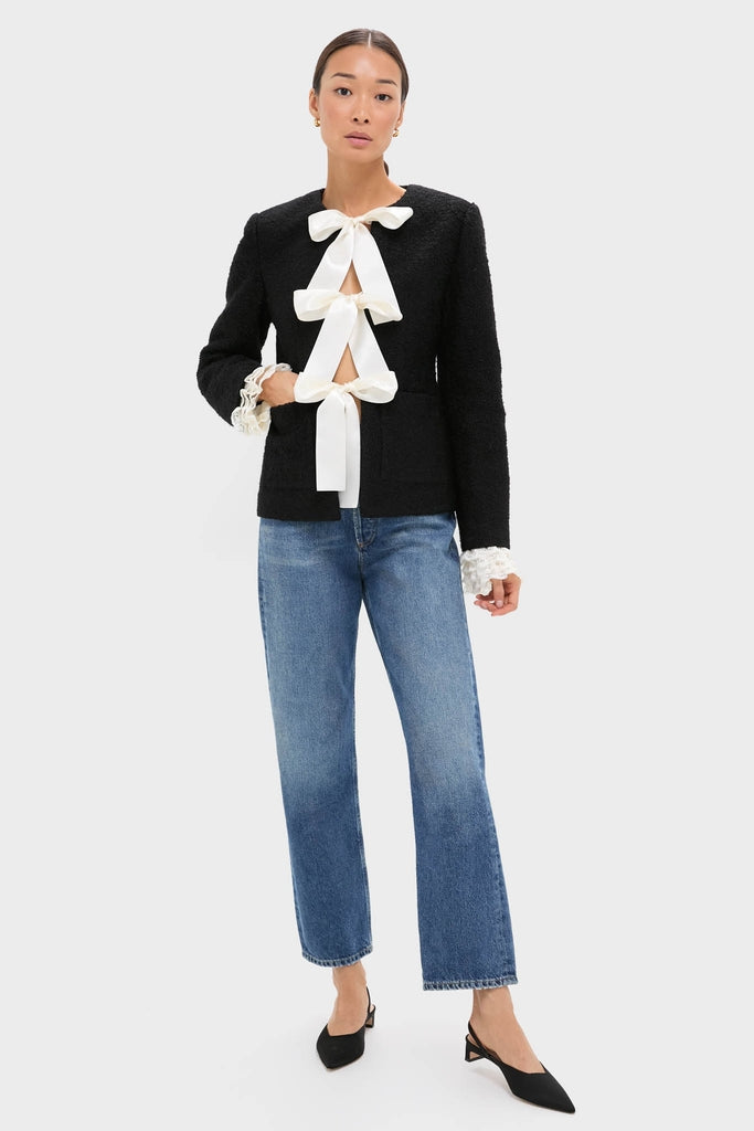Model wearing the Black Seraphine Solid Bow Jacket, a classic, high-end piece with satin bows and lace cuffs, paired effortlessly with blue jeans and slingback heels.