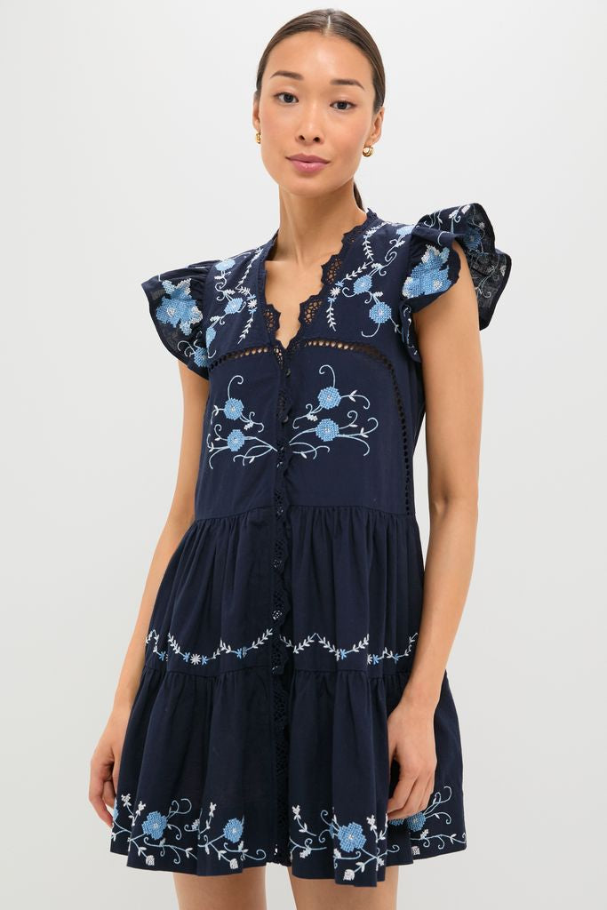 Exclusive Navy Edwina Embroidery Tunic Dress with classic flutter sleeves, intricate floral cross-stitch details, and a tiered silhouette, embodying effortless, high-end style.