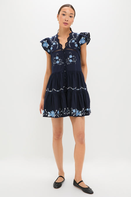 Exclusive Navy Edwina Embroidery Tunic Dress modeled with elegance, featuring classic floral embroidery, effortless tiered design, and fun flutter sleeves for a high-end, feminine look.