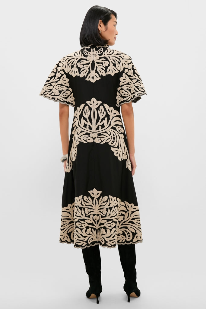 Woman wearing the Black Alexandra Embroidery Short Sleeve Midi Dress with bold floral appliqué, paired with knee-high boots, embodying a classic, effortless, and high-end style.