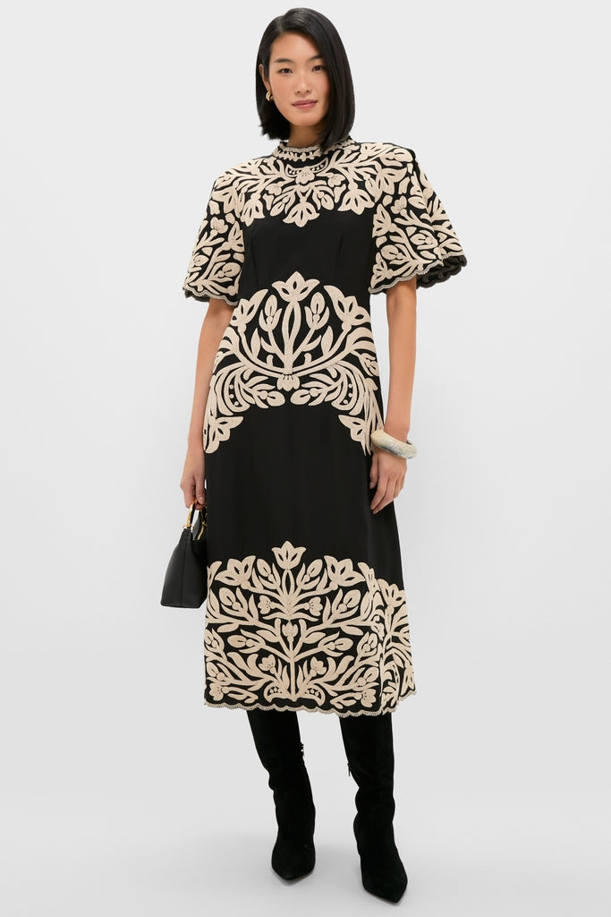 Woman in Black Alexandra Embroidery Short Sleeve Midi Dress with floral panels, paired with knee-high boots and accessories, exuding a classic, effortless, high-end style.