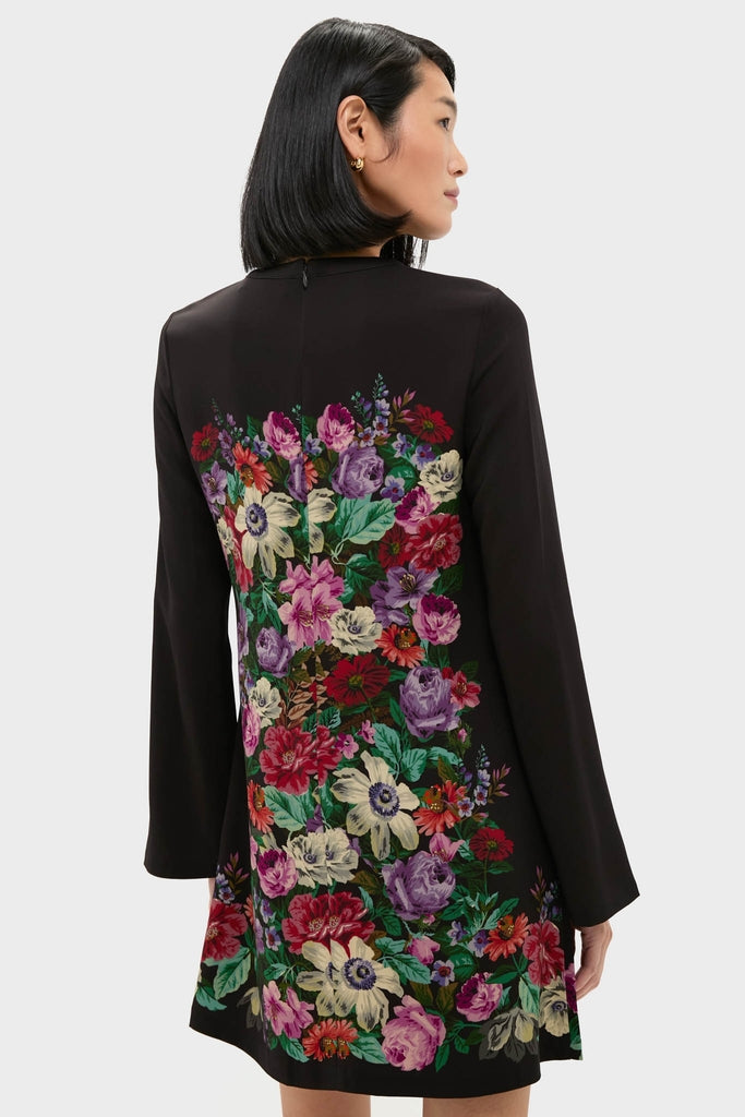 A woman models the Multi Viktoria Print Long Sleeve Mini Dress, featuring an effortless, high-end floral design on the back, embodying Tuckernuck's classic and fun style.