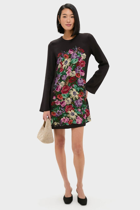 Model wearing the Multi Viktoria Print Long Sleeve Mini Dress, featuring a classic, effortless multicolored floral design, paired with a chic woven clutch and black pumps.