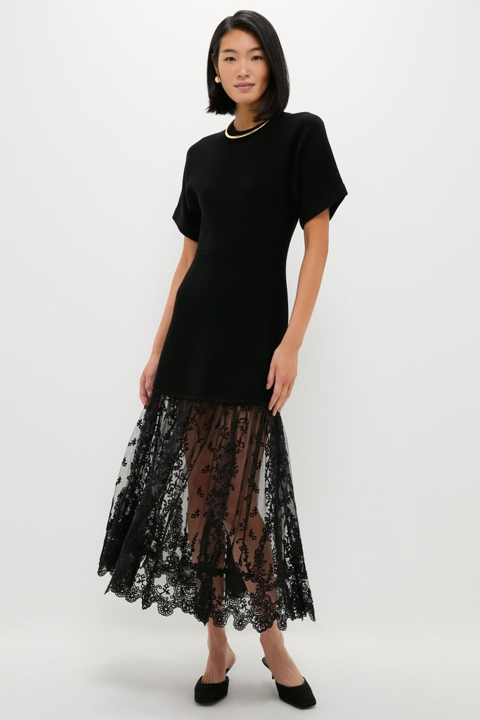 Black Diane Knit Lace Combo Knit Dress: A classic, effortless high-end design featuring a short-sleeved black top and sheer lace skirt with floral embroidery, styled with minimal gold jewelry.