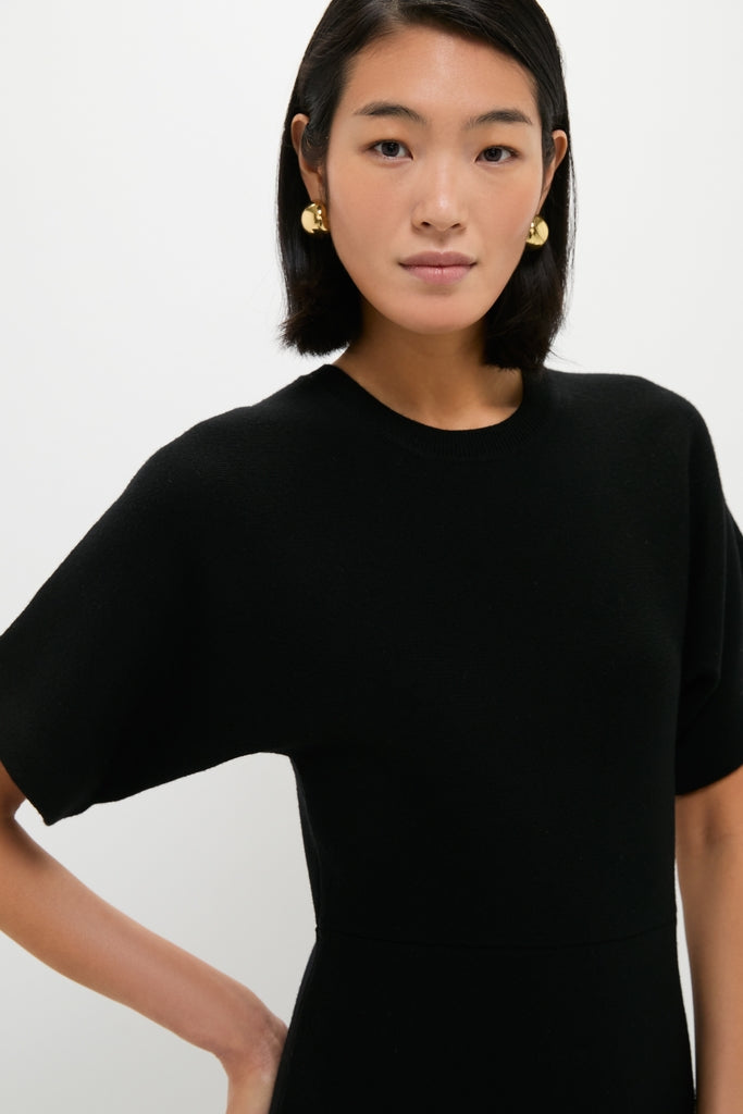 Asian woman in a Black Diane Knit Lace Combo Knit Dress, featuring a classic, effortless design with short sleeves and a round neckline, paired with statement gold earrings.
