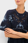 Exclusive Navy Edwina Embroidery Midi Dress with intricate light-blue floral cross-stitch embroidery, open-lace panels, and short bell sleeves, exuding a classic, effortless, and high-end style.