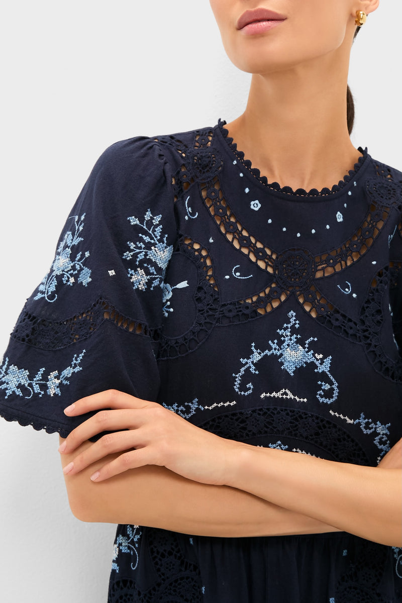 Exclusive Navy Edwina Embroidery Midi Dress with intricate light-blue floral cross-stitch embroidery, open-lace panels, and short bell sleeves, exuding a classic, effortless, and high-end style.