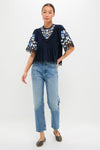 Exclusive Navy Edwina Embroidery Short Sleeve Top, a classic, effortless blouse with intricate floral embroidery and bell sleeves, paired with light-wash jeans for a high-end, fun look.