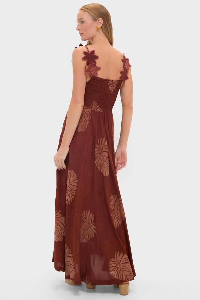 Model showcases the Rust Toye Dress, a classic, effortless maxi with a smocked bodice, petal straps, and abstract motifs, embodying Tuckernuck's fun, high-end aesthetic.