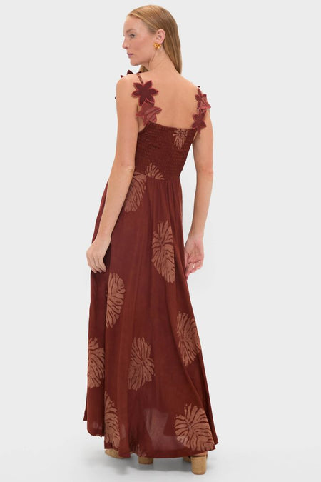 Model showcases the Rust Toye Dress, a classic, effortless maxi with a smocked bodice, petal straps, and abstract motifs, embodying Tuckernuck's fun, high-end aesthetic.