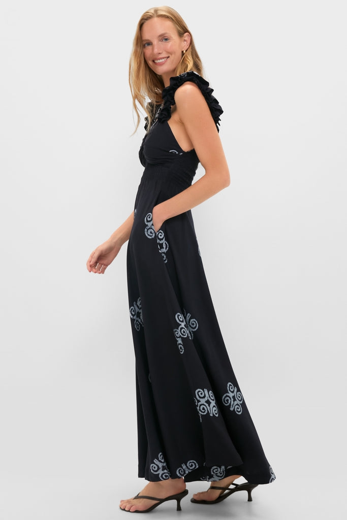 Young woman in profile wearing the classic Black Ibukun Dress with swirl motifs, ruffled straps, empire waist, and pockets, embodying an effortless, high-end style.