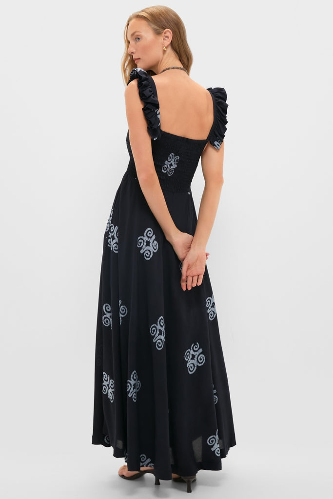 Young woman models the Black Ibukun Dress, featuring a classic smocked bodice, ruffled straps, and a full skirt with an effortless swirl motif.