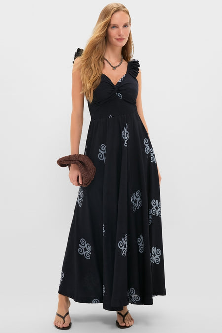 Young woman models the Black Ibukun Dress, a classic, high-end maxi with a twist-front bodice and subtle pattern, effortlessly paired with a textured clutch.