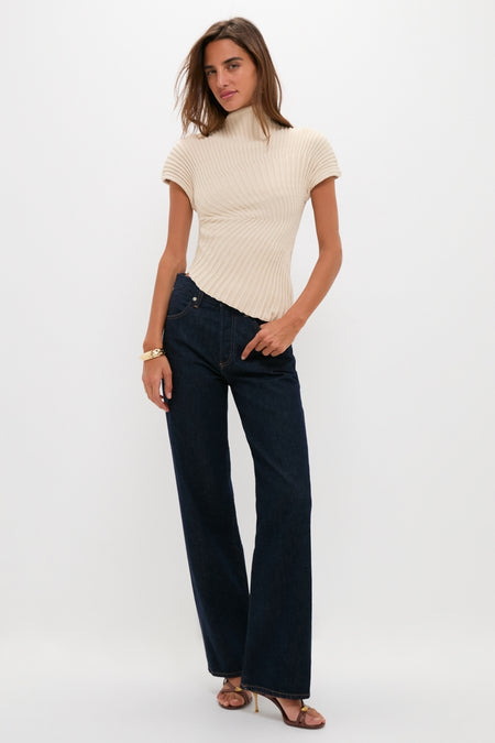 Model in classic, high-end Beach Annemie Top with asymmetrical hem and flared cap sleeves, paired effortlessly with dark jeans and fun, strappy heels.