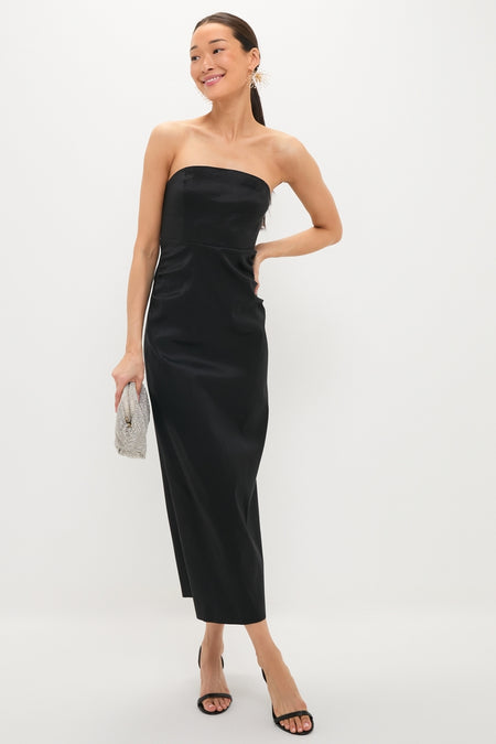 Woman in a classic black dress, showcasing an effortless, high-end style with Pearl Damita Earrings and a silvery clutch, embodying Tuckernuck's fun and confident vibe.