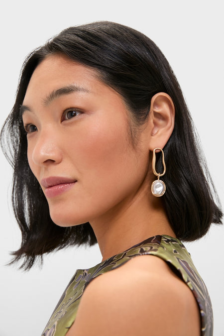 Woman wearing Brushed Brass Vera Earrings, featuring a classic, effortless design with a gold-tone loop and pearl-like pendant, embodying Tuckernuck's fun and high-end style.