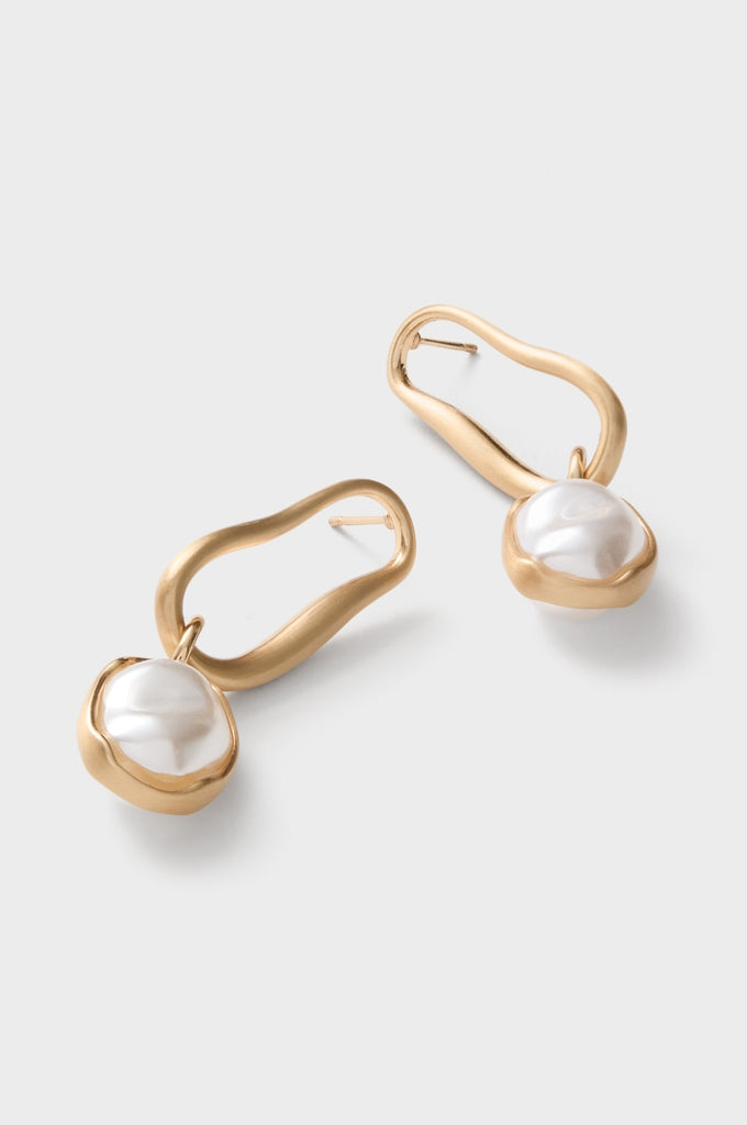 Brushed Brass Vera Earrings feature classic, effortless gold-tone loops with baroque pearls, offering a high-end, fun accessory for those seeking stylish elegance.