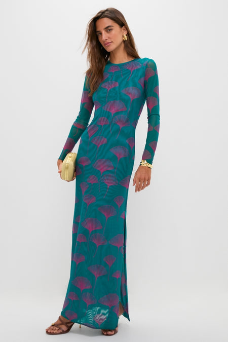 Woman in a teal maxi dress with magenta leaf motif, modeling classic Saddle Valeska Sandals. The high-end sandals feature an asymmetrical strappy design and gold hardware, creating an effortless, fun look.