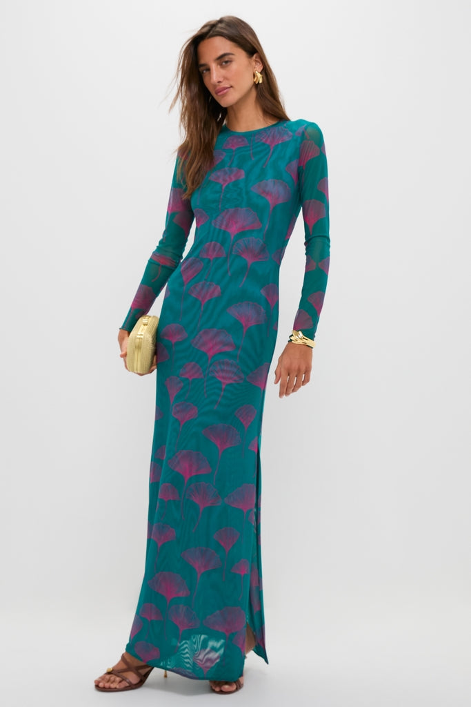 Woman in a teal maxi dress with magenta leaf motif, modeling classic Saddle Valeska Sandals. The high-end sandals feature an asymmetrical strappy design and gold hardware, creating an effortless, fun look.