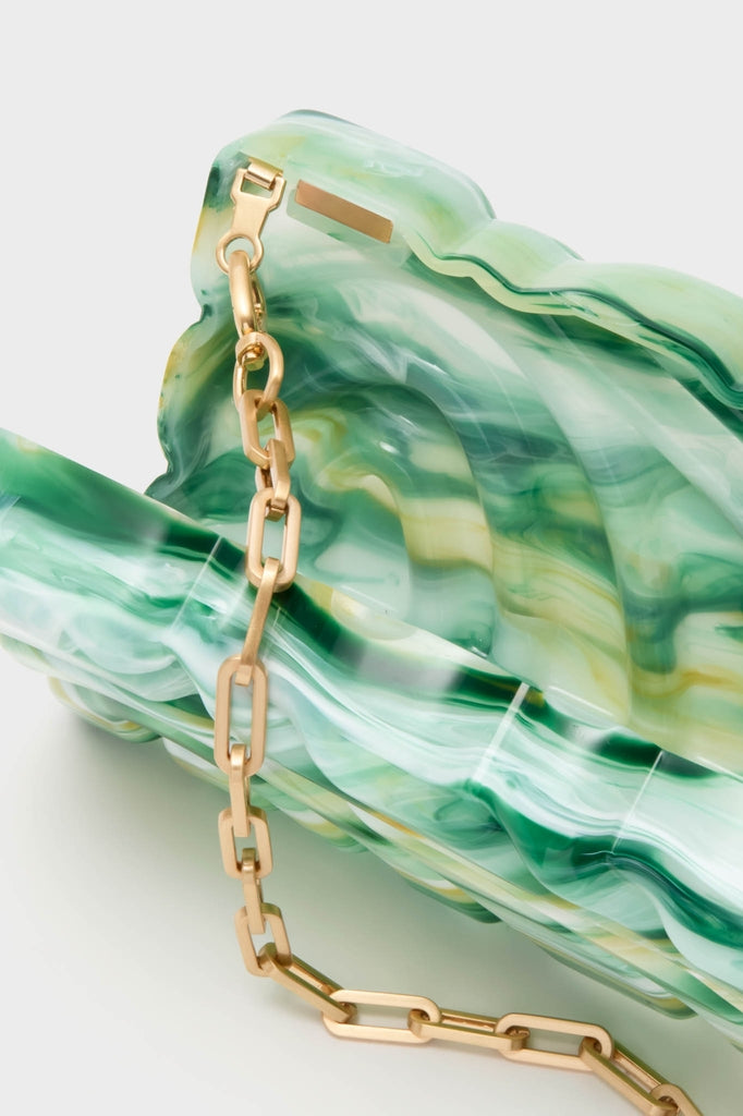 Sage Aura Clutch: A classic, sculptural shell-shaped mini handbag in swirled green acrylic with a glossy, marbled finish and a chunky gold-tone chain strap. Effortlessly high-end and fun.