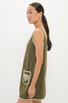 Slim person in profile wearing the Fern Embroidered Mini Terrycloth Dress Coverup. This classic, effortless olive-green dress features white piping and a fun seashell pocket, exuding high-end style.