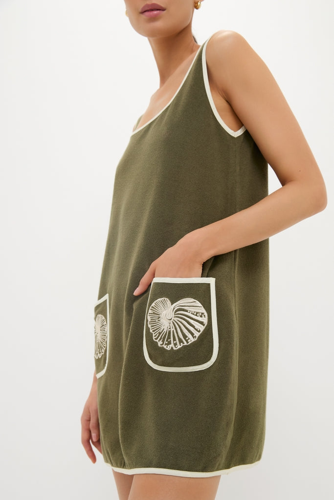 Woman wearing the Fern Embroidered Mini Terrycloth Dress Coverup, a classic, effortless olive-green tunic with seashell pockets and white trim, embodying fun, high-end style.